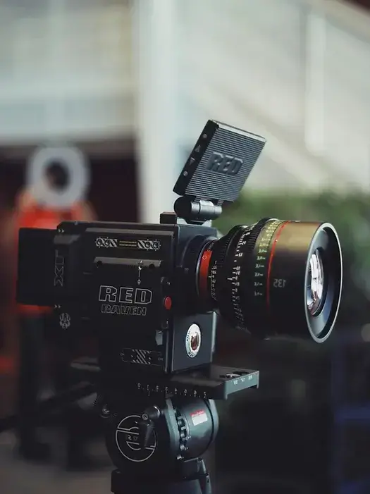 Professional RED Raven camera on tripod, equipped for high-quality video production in a studio setting.